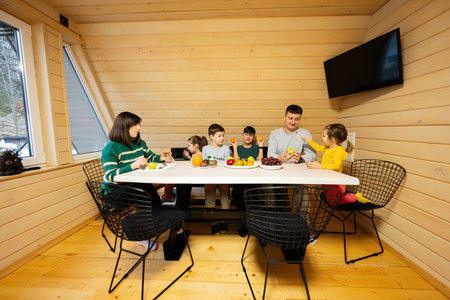 Family with four kids eat fruits in wooden country house on weekend.の写真素材