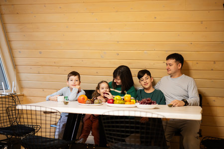 Family with three kids eat fruits in wooden country house on weekend.の写真素材