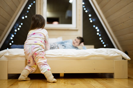 Children in soft warm pajamas playing at wooden cabin home. Concept of childhood, leisure activity, happiness. Brother and sister having fun and playing together.の写真素材