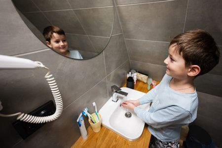 Boy washes hands in the sink at bathroom.の写真素材