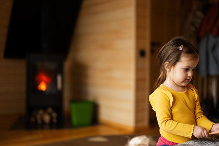 Baby girl playing against fireplace at cozy comfortable old weather easy indoors heating.の写真素材