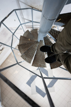Male tourist legs on spiral staircase of tower.