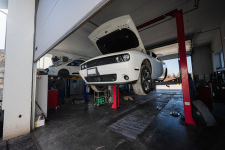 Muscle car with open hood at service repair station in lift.の写真素材