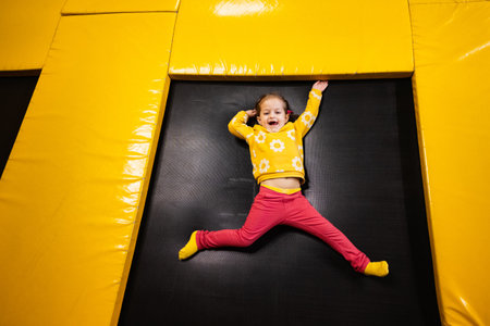 Baby girl kid lying on trampoline at playground park. Child in motion during active entertaiments.の写真素材