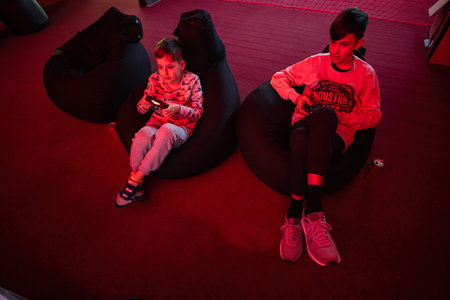 Two boys gamers play gamepad video game console in red gaming room.の写真素材