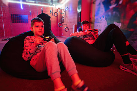 Two boys gamers play gamepad video game console in red gaming room.の写真素材