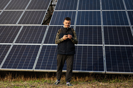 Man with mobile phone on the background of solar panels.  Eco energy.