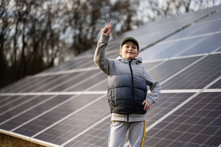 Boy child show finger up on the background of solar panels.  Eco energy.の写真素材