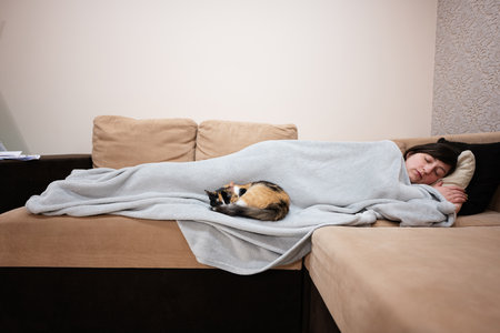 Young woman lying and sleep in bed at home with her cat.