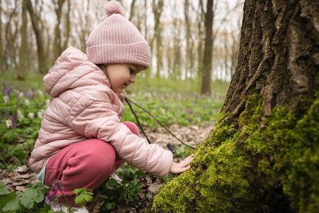 A little researcher of the forest. The girl touches moss on the tree.の写真素材