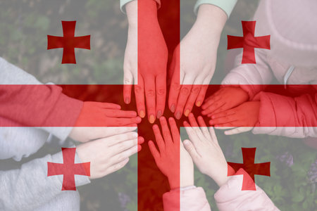Hands of kids on background of Georgia flag. Georgian patriotism and unity concept.