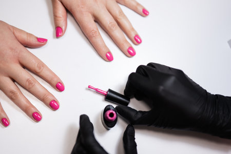 Close up hands of manicure master working with female client in beauty salon. Manicurist makes woman nails.の写真素材