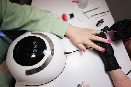 Close up hand of manicure master working with female client in beauty salon. Manicurist makes woman nail.の写真素材