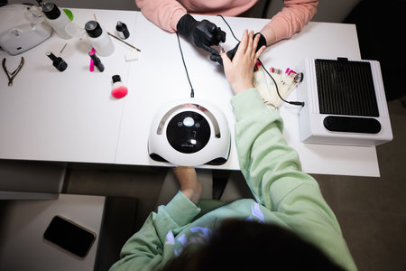 Top view of manicure master working with female client in beauty salon. Manicurist makes woman nail.の写真素材