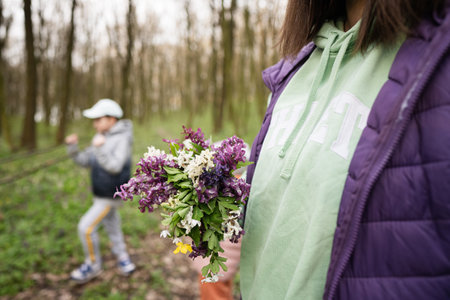 Woman hand with spring bouquet of flowers on forest. Outdoor leisure concept.