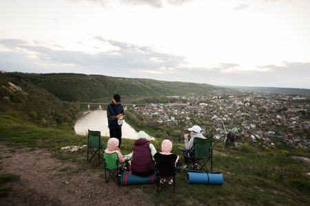 Family hiking on vacation, having evening picnic on top of the mountain, looking at beautiful canyon landscape.の写真素材