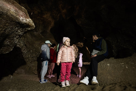 Family tourists walking in cave and explore it.の写真素材