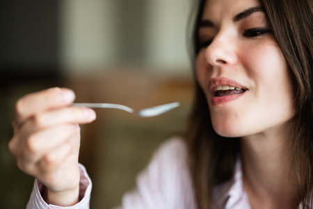 Young beautiful brunette woman sit in coffee shop cafe restaurant indoors and eat, fork near the mouth.の写真素材