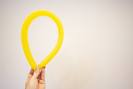 Hand holding yellow rubber tube on white background. Copy space for text.の写真素材