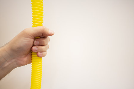 Hands holding a yellow hose on a white background close-upの写真素材