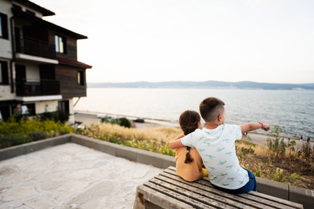 Back view of boy and girl sitting on bench and looking at sea in Nessebar.の写真素材
