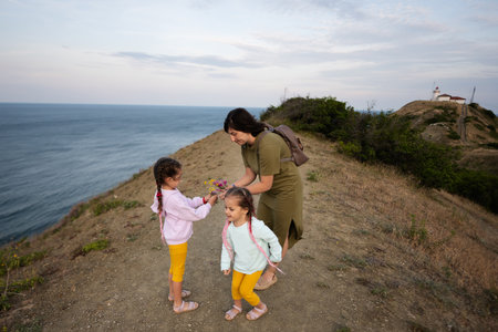 Mother and two daughters with wild flowers against sea from the top of the mountain. Cape Emine, Black sea coast, Bulgaria.の写真素材