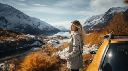 Young woman standing near car and looking at mountain lake in winter day.の素材