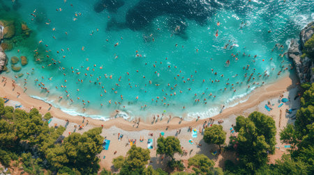 An aerial shot captures a bustling beach scene with numerous people swimming in clear waters and lounging on the sand. Perfect for vacation and travel themes.の素材