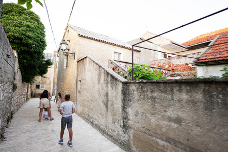 Family walking and exploring a picturesque European village Nin, Croatia with historic stone...
