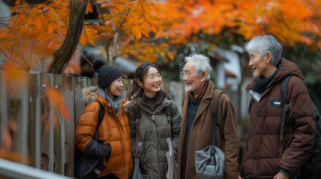 Friendly interaction between multigenerational neighbors outdoors. Two younger and two older individuals enjoying a pleasant autumn conversation amidst colorful foliage.の素材