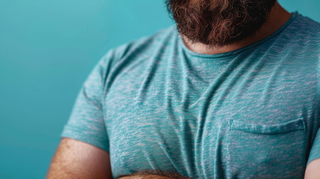 Close-up of an overweight man in a tight shirt, standing against a light blue background, showing body positivity and everyday fashion.の素材