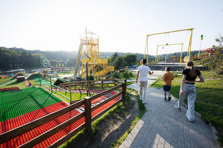 Teens walks through a vibrant amusement park on a sunny day, enjoying the various attractions and scenic views. Fun, leisure, and bonding atmosphere in a playful outdoor setting.の写真素材