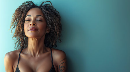 A serene middle-aged woman stands confidently against a teal background, embodying self-assurance and body positivity. She exemplifies beauty and empowerment with her relaxed, peaceful expression.の素材