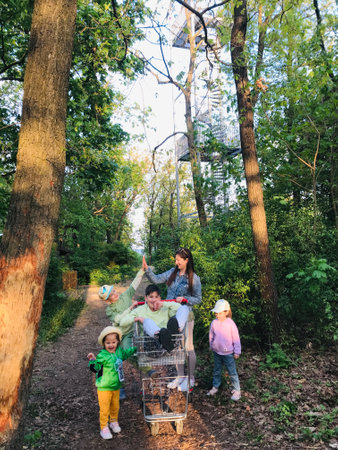 A joyful family spends a playful day outdoors, pushing a shopping cart along a wooded path. Laughter and nature combine for a fun-filled afternoon in the fresh air.の写真素材