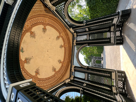 This image captures an elegant garden pavilion featuring a stunning ornate ceiling, providing an exquisite outdoor architectural experience beneath sunny skies and lush greenery in Schonbrunn palace, Austria.の写真素材