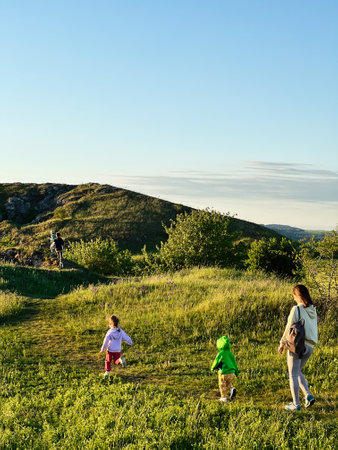 A family enjoys a hike on a sunny day, exploring the lush greenery and scenic hills. Children and parents walk along a nature trail, experiencing outdoor adventure and togetherness.の写真素材