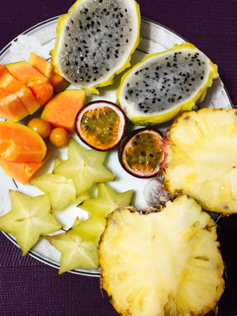 An artfully arranged plate showcasing a vibrant array of tropical fruits, including pineapple,...