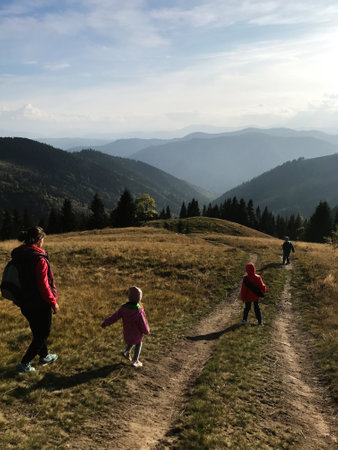 A family enjoys a refreshing hike along a picturesque mountain trail. The scene captures the beauty...