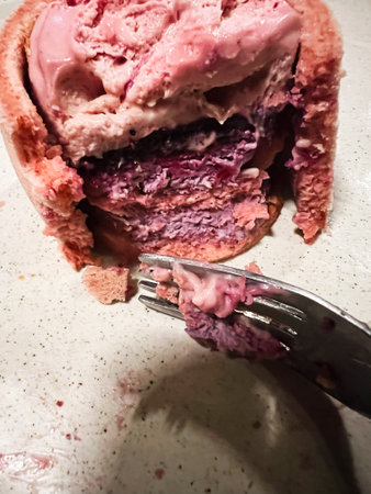 Delicious close-up of pink and purple ice cream cake layers with a textured, creamy appearance,...