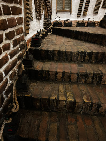 A rustic brick staircase adorned with vintage irons and ropes, offering a nostalgic glimpse into historic craftsmanship and interior design, invoking a sense of history and heritage.の写真素材