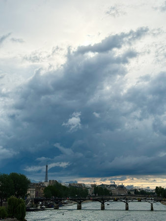 A breathtaking view of Paris featuring the iconic Eiffel Tower beneath dramatic storm clouds and a beautiful skyline over the Seine River.の写真素材