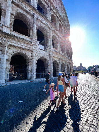 A group of tourists enjoys a sunny day exploring the historic Colosseum in Rome. The iconic architecture and bright sunlight create a vibrant travel atmosphere.の写真素材