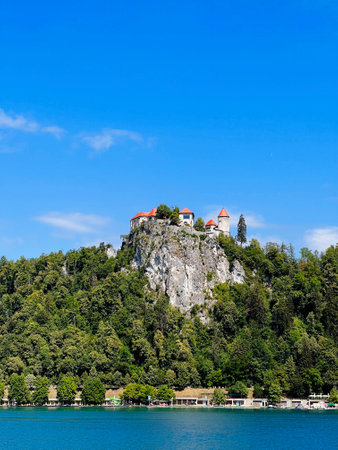 Historic castle perched on a rocky cliff, overlooking a serene lake. Surrounded by dense greenery, this picturesque scene captures the essence of tranquility and natural beauty. Bled, Slovenia.の写真素材