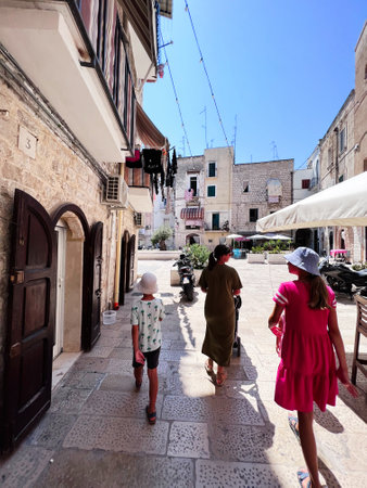 A family strolls through a charming stone-paved alley in a historic European village, basking in the...