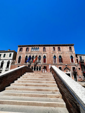 The image features a historic brick building with ornate windows, captured from the steps leading up. Bright blue sky enhances the architectural beauty.の写真素材