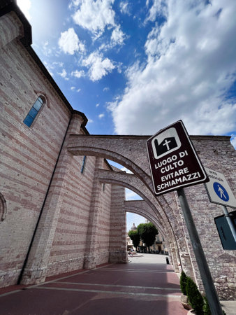 Stone archway stands against a vivid blue sky, capturing the serene atmosphere of a historic site. A sign provides details of the location, adding authenticity to the scene. Assisi, Italy.の写真素材