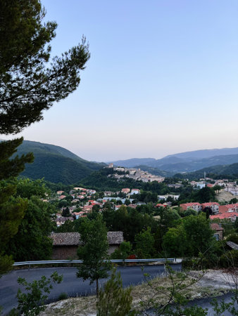 A picturesque hillside village surrounded by lush greenery under a serene, clear sky. The charming houses and natural landscape create a tranquil ambiance, perfect for relaxation and appreciation of nature. Nocera Umbra, Italy.の写真素材