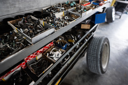 Close-up view of various metal bolts, nuts, and fasteners organized in boxes on a workshop shelf, ideal for automotive or mechanical purposes.の写真素材