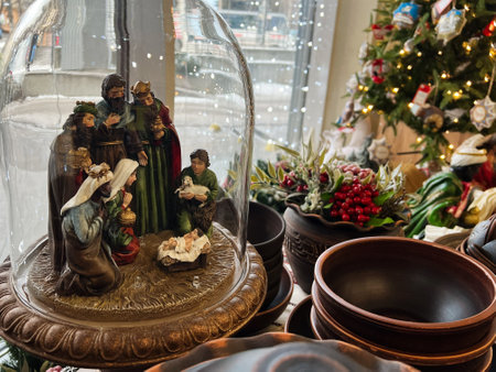 Elegant display of a nativity scene within glass dome surrounded by holiday decorations and bowls. A lit Christmas tree and festive greenery create a warm, joyful atmosphere celebrating the season.の写真素材