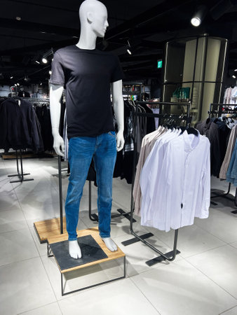 A clothing store interior featuring a dressed mannequin with casual attire alongside hanging...